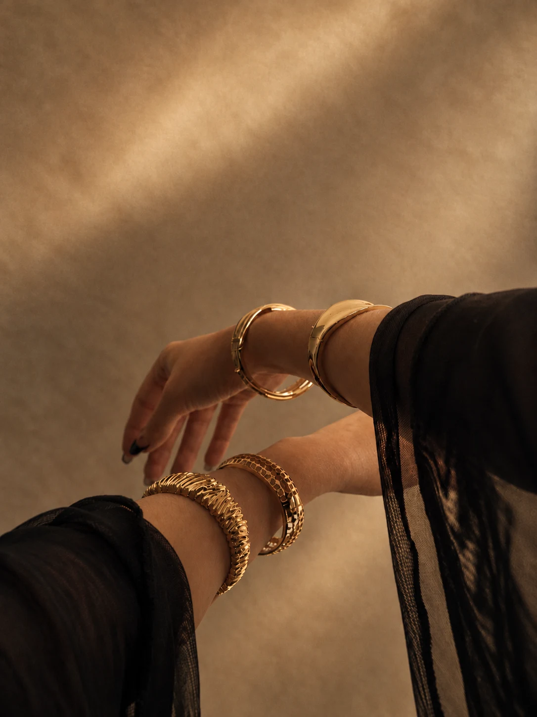 Pulseiras douradas em uma composição de mãos e braços